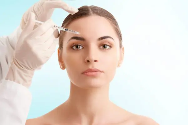 A stunning woman receiving treatment from the surgeon for forehead wrinkles.